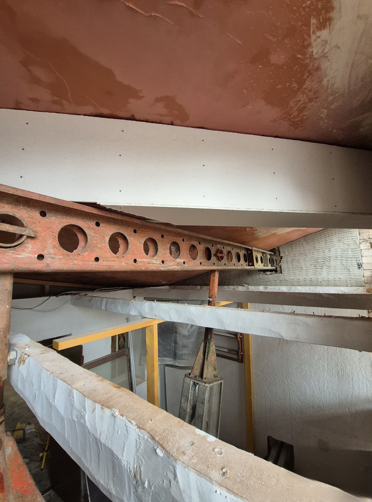Slimshore header beam packed beneath a balcony soffit to carry the roof truss back-propping