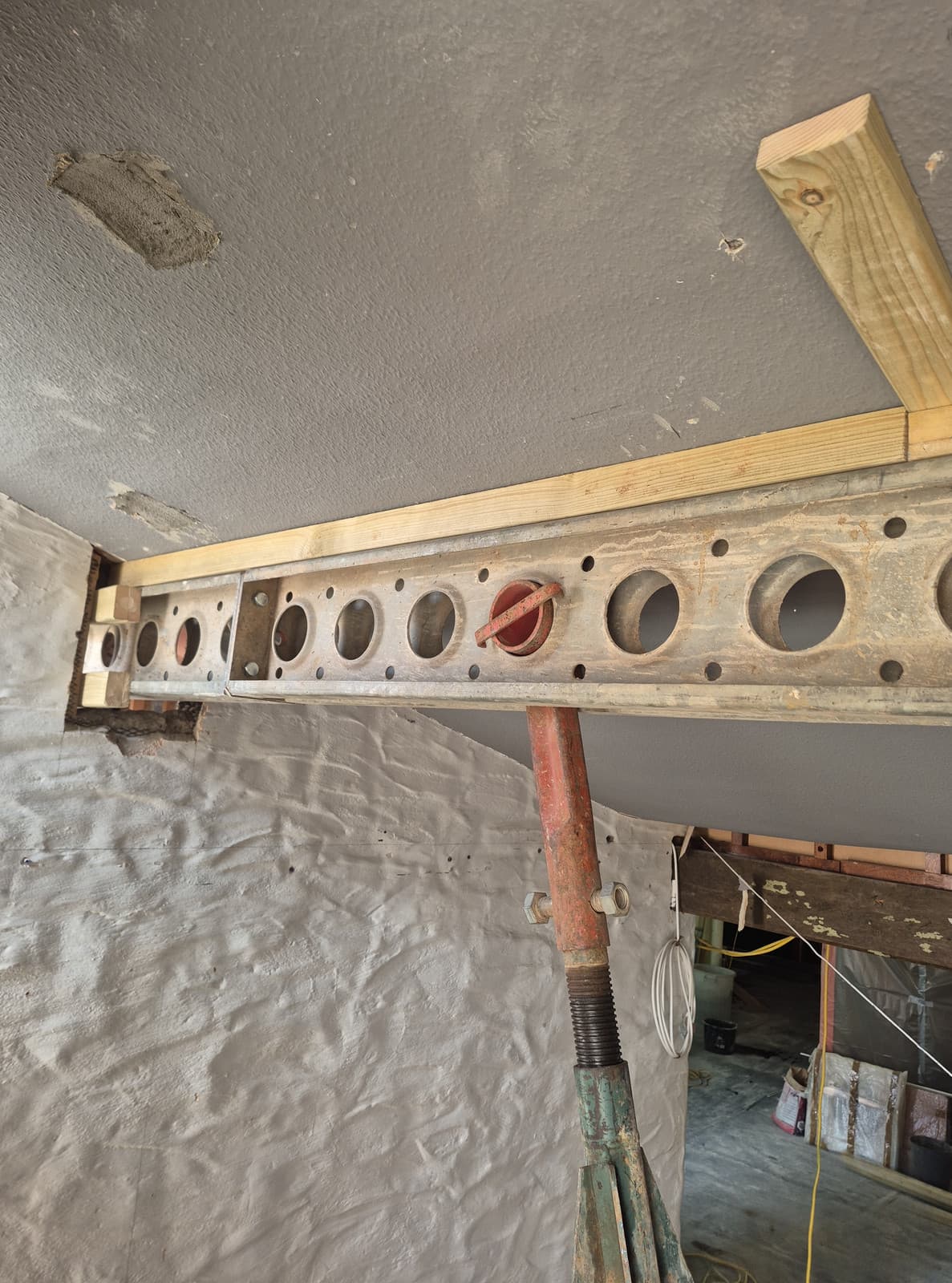 Slimshore header beam seated into a wall pocket with timber packing to the soffit, on an adjustable jack