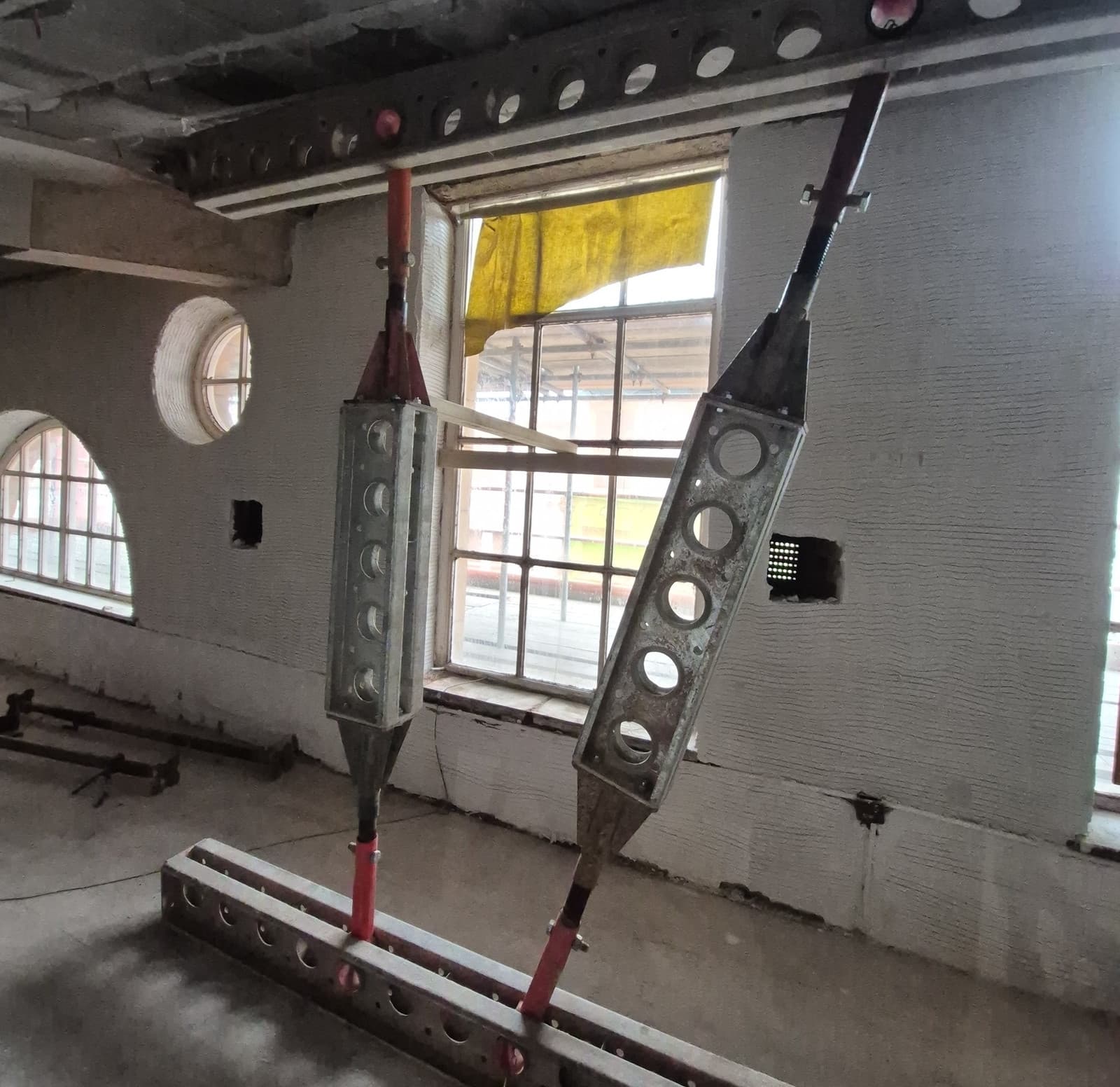 Raking and vertical Slimshore props with spade end links pinned to continuous header and spreader beams on the first floor
