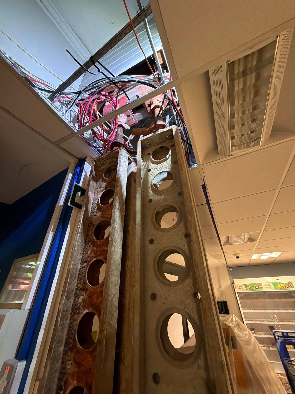 Paired 2.7m Slimshore soldiers beside the ground-floor shop entrance, rising into the ceiling void to existing steel beams