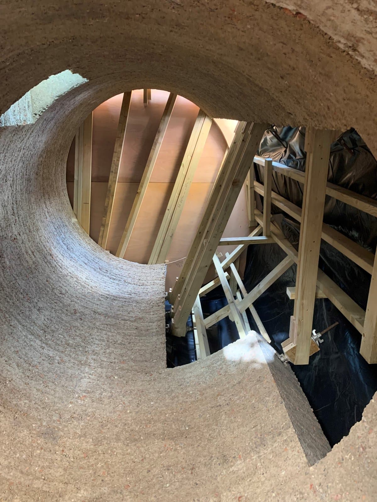 Looking through a curved rammed earth wall to the timber falsework and plywood shutter inside