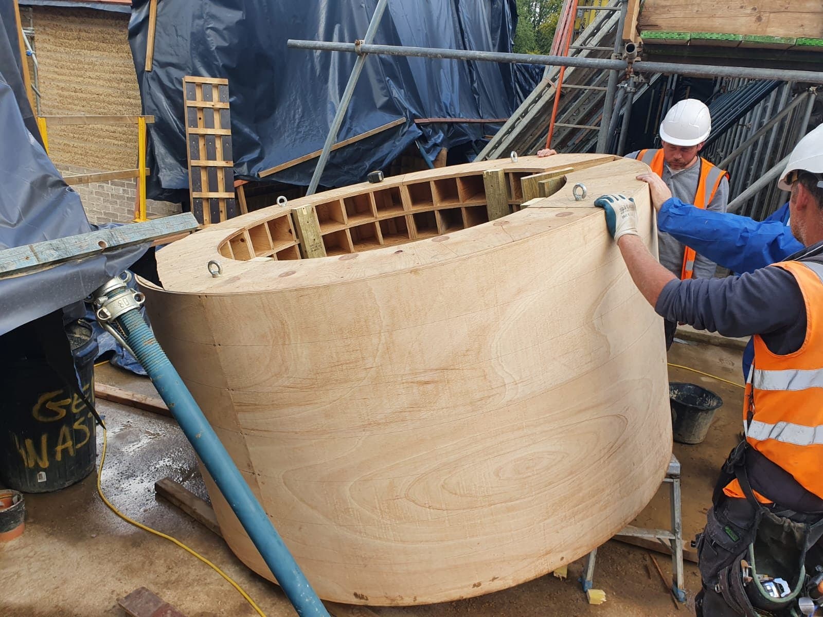 Operatives positioning the curved plywood internal timber shutter for the rammed earth wall