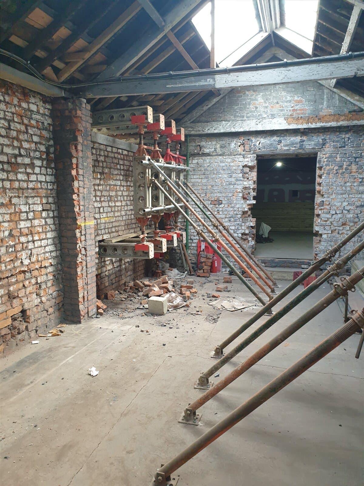 Slimshore reverse needling and push-pull props beside an existing opening through a load-bearing brick wall
