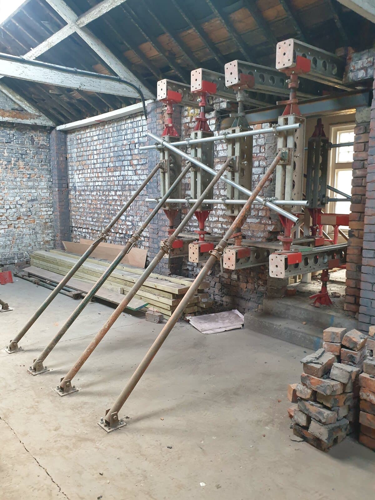 Slimshore reverse needling bay with four needle beams and raking push-pull props beneath the roof trusses on the top floor