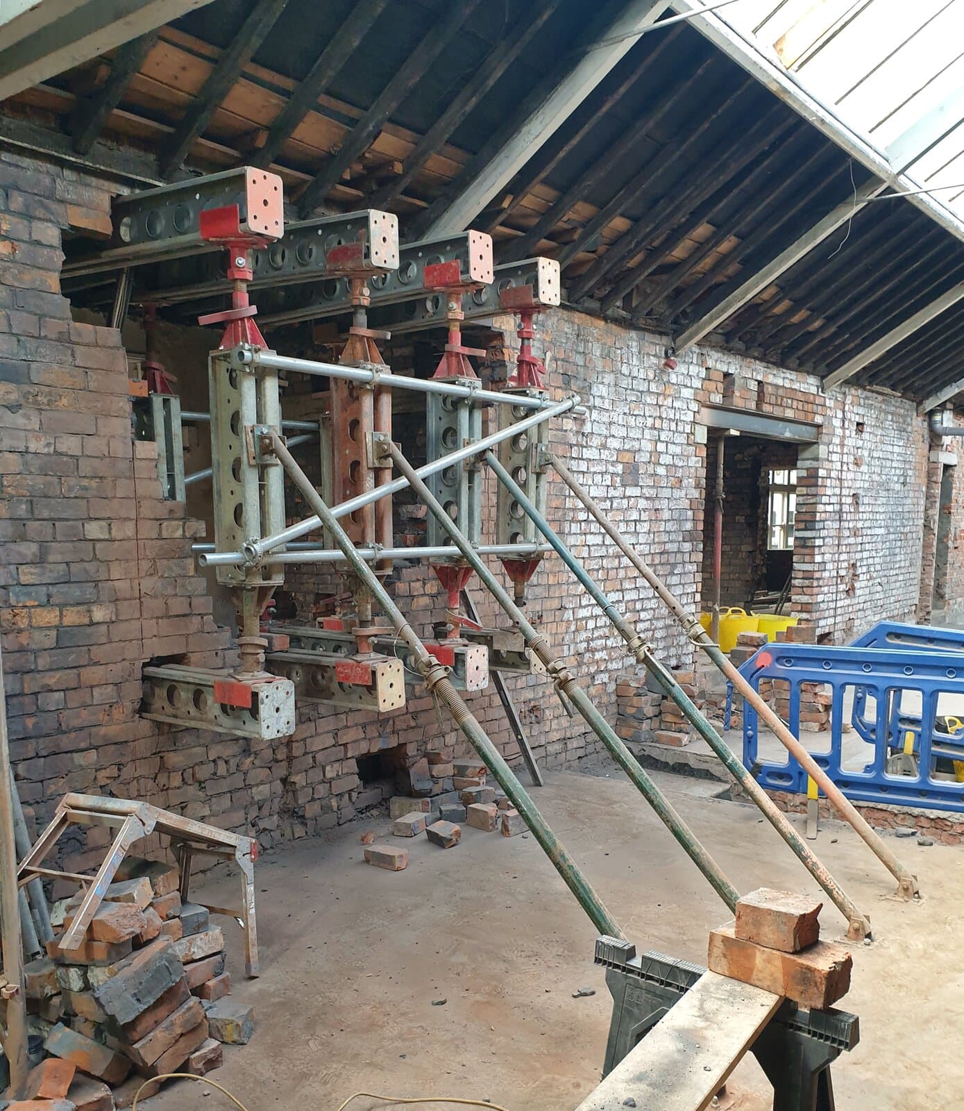 Slimshore soldiers between upper needle beams and reverse needles, with scaffold tube bracing and push-pull props