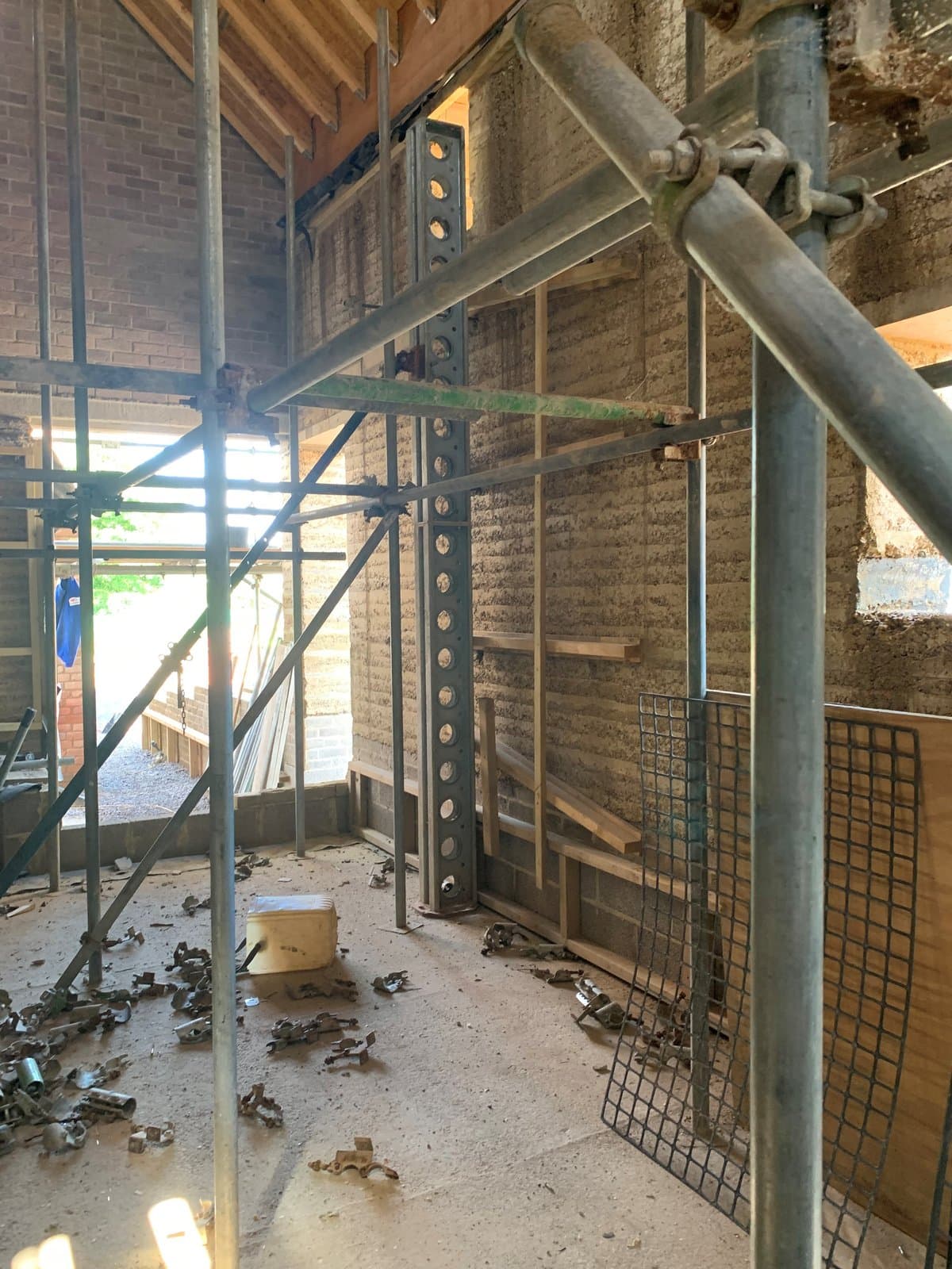 Slimshore soldier and scaffolding inside the house against a rammed earth wall during construction