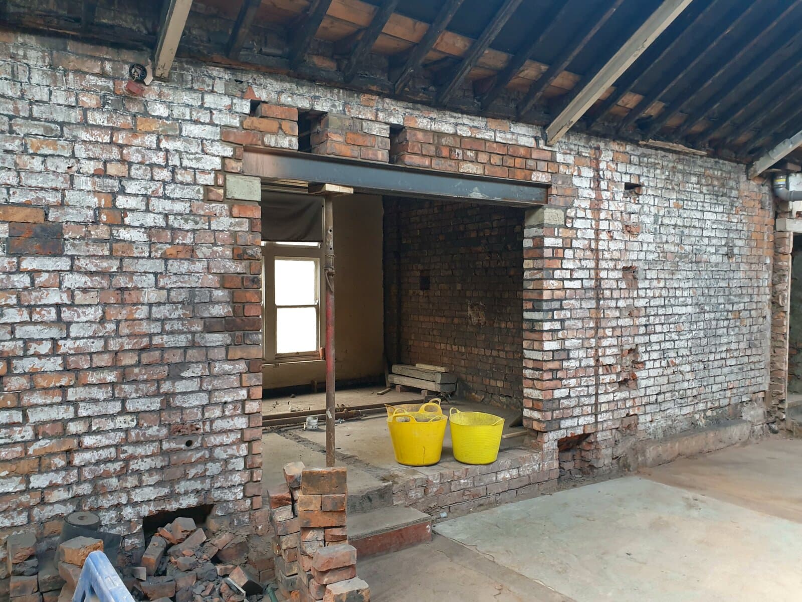 Completed structural opening through a load-bearing masonry wall with the new steel beam in place